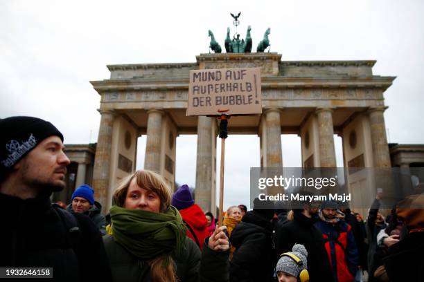 Demonstrator holds a placard in German saying "Open your mouth outside the bubble" during a pro-democracy demonstration in front of the Brandenburg...