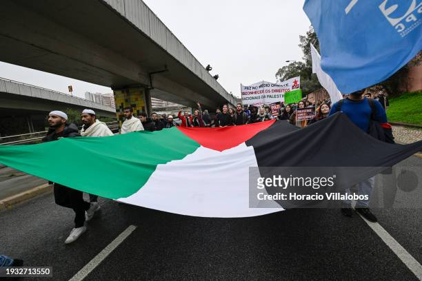 Demonstrators hold a large Palestinian flag while marching from the U.S Embassy to Israeli Embassy during a protest "for peace in the Middle East,...