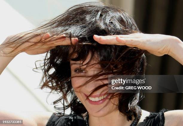 Academy award winning French actress Juliette Binoche struggles to keep her hair in place during windy conditions on the steps of the Sydney Opera...