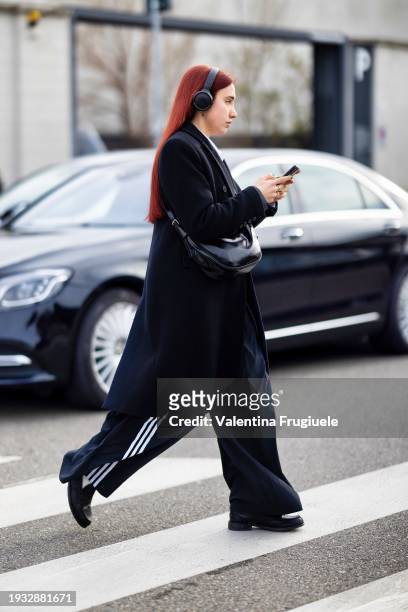 Guest is seen wearing black headphones, a black long coat, a black cross-body bag, black leather loafers, white socks and black and white striped...