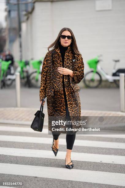 Guest wears sunglasses, a brown and orange leopard print trench coat, black crop pants, a bag, pointed shoes, outside Prada, during the Milan Fashion...