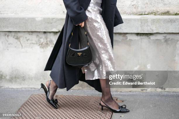 Caroline Daur wears a black long coat, a silver shiny sequined low neck midi dress long dress, black tights, a Prada bag, pointed shoes with kitten...