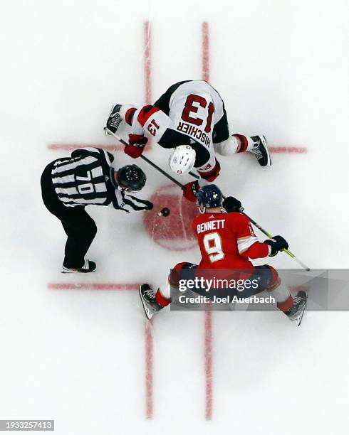 Linesman Derek Nansen drops the puck between Nico Hischier of the New Jersey Devils and Sam Bennett of the Florida Panthers at the Amerant Bank Arena...