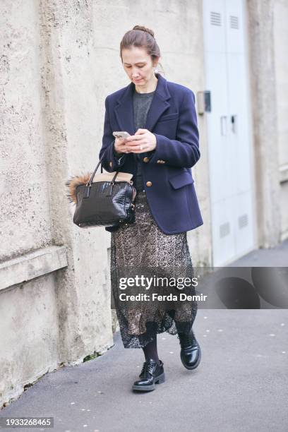 Guest wears dark blue jacket and midi skirt and black bag outside Prada show during the Milan Fashion Week - Menswear Fall/Winter 2024-2025 on...