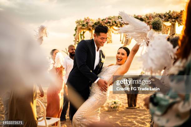 newlyweds celebrating with their guests at beach wedding ceremony - trouwfeest stockfoto's en -beelden
