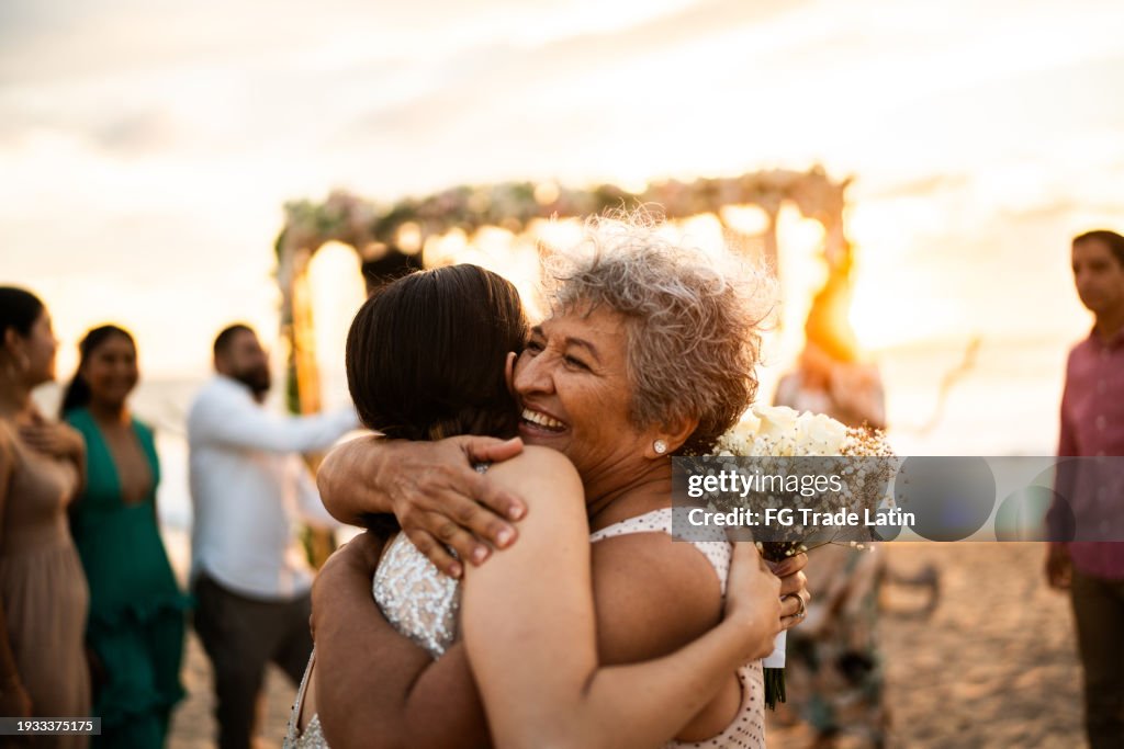 Bride embracing her grandmother after wedding ceremony on the beach