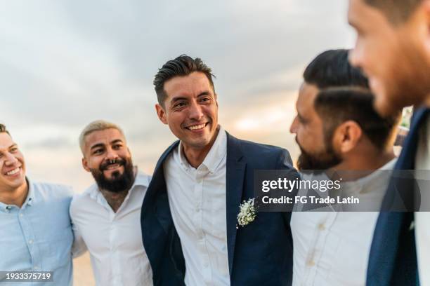 groom talking with his friends in the wedding party on the beach - wedding role stock pictures, royalty-free photos & images