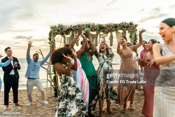 bride's friends trying to catch the bouquet at the beach wedding party - catching bouquet stock pictures, royalty-free photos & images