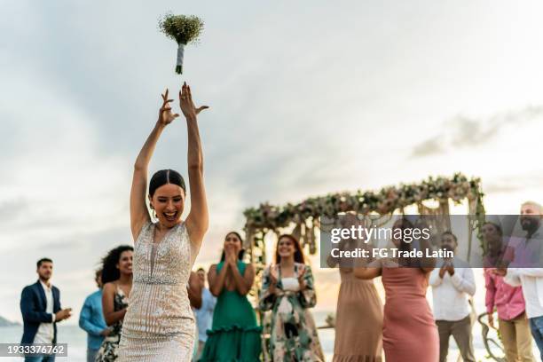 sposa che lancia il bouquet ai suoi amici sulla festa di nozze in spiaggia - bouquet foto e immagini stock