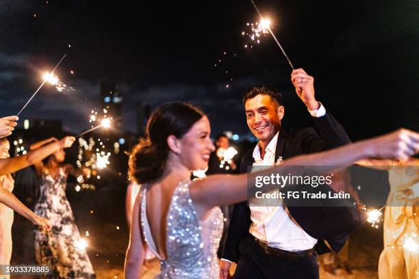 bride and groom using sparklers with their wedding guests on the beach wedding party - noivo papel em casamento imagens e fotografias de stock