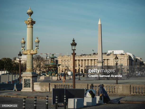 Homeless woman sits at Concorde Square on January 16, 2024 in Paris, France. Insufficient investment in social housing over the last decade has led...