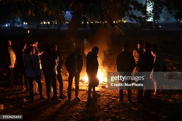 Visitors are making a fire with homeless people to keep warm in Suhrawardy Park during a winter night in Dhaka, Bangladesh, on January 17, 2024.