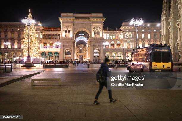 Person is walking in Piazza Duomo , against the backdrop of the facade of Galleria Vittorio Emanuele II, in Milan, Italy, during the Christmas...