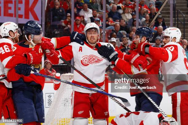 Sam Bennett and Matthew Tkachuk of the Florida Panthers take on Ben Chiarot of the Detroit Red Wings during first period action at the Amerant Bank...