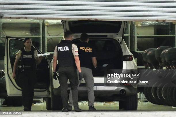 January 2024, Ecuador, Guayaquil: Police officers in protective vests examine the car of the slain public prosecutor César Suárez in Guayaquil,...