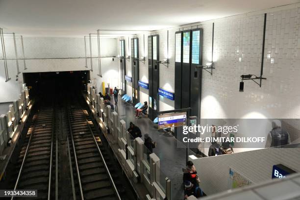 Commuters stand on the platform of the 'Basilique de Saint-Denis' metro station in Saint-Denis, on the outskirts of Paris, on January 18, 2024. A...