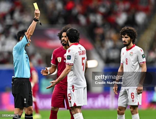 Referee Hiroyuki Kimura is showing a yellow card to Manuchekhr Safarov of Tajikistan during the AFC Asian Cup 2023 match between Qatar and Tajikistan...