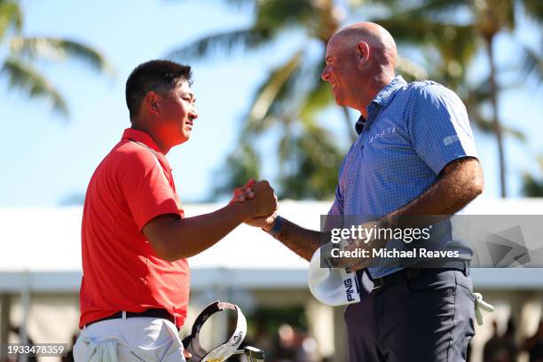 Carl Yuan of China and Stewart Cink of the United States embrace on the 18th green after completely their round during the final round of the Sony...