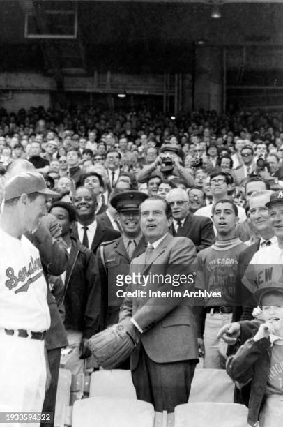 American president Richard Nixon , center, wearing a Wilson baseball glove, gets ready to throw the first pitch to open the season at Robert F...