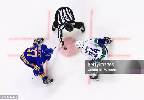 Linesman Tommy Hughes prepares to drop the puck for a face-off between Casey Mittelstadt of the Buffalo Sabres and Pius Suter of the Vancouver...