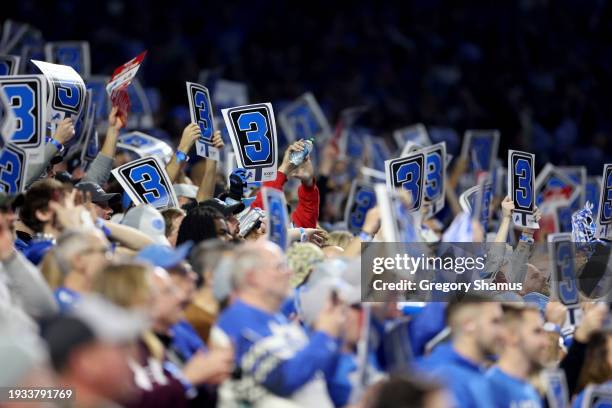 Detroit Lions fans hold up cards with the number three on them during the third quarter against the Los Angeles Rams in the NFC Wild Card Playoffs at...