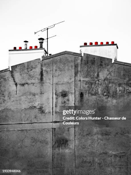 grey and patinated gable with chimneys and rake antenna of an old building in paris, france. day light. cloudy sky.
photograph in black and white, except for the terracotta chimneys which have their original red color. - paris-red-light-district stockfoto's en -beelden