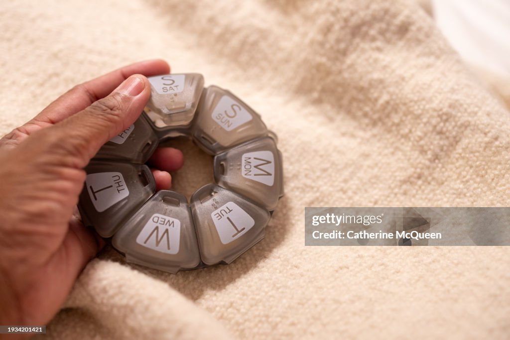 Black woman holding plastic pill case organizer