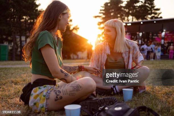 happy women talking on a music festival at sunset. - music festival grass stock pictures, royalty-free photos & images