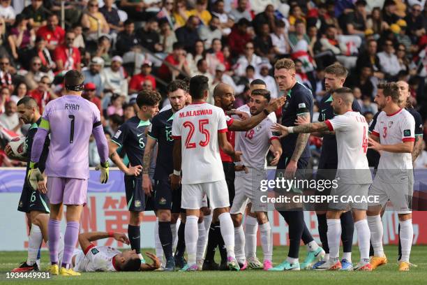 Syria's forward Pablo Sabbag lies on the ground as Syria and Australia's players speak with Emirati match referee Adel Al-Naqbi during the Qatar 2023...