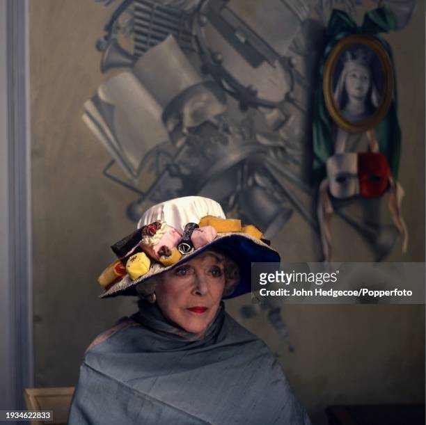 English actress, aristocrat and socialite Lady Diana Cooper posed wearing a hat decorated with motifs of various kinds of cake in England in 1982.