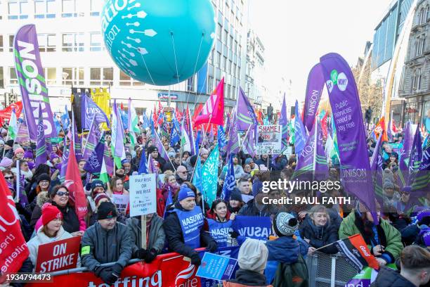 People hold placards as they attend a rally in support of striking public sector workers in Belfast on January 18, 2024. The mass strike in Northern...