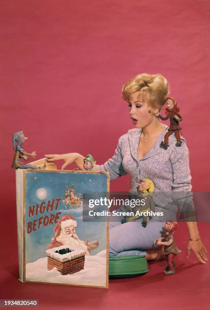 Barbara Eden with elves as she ready 'The Night Before Christmas' story book in a publicity pose circa 1964.