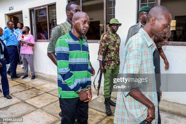 Self-proclaimed pastor Paul Nthenge Mackenzie walks surrounded by Kenya Police Officers and other defendants as he appears at the Shanzu Law Courts...