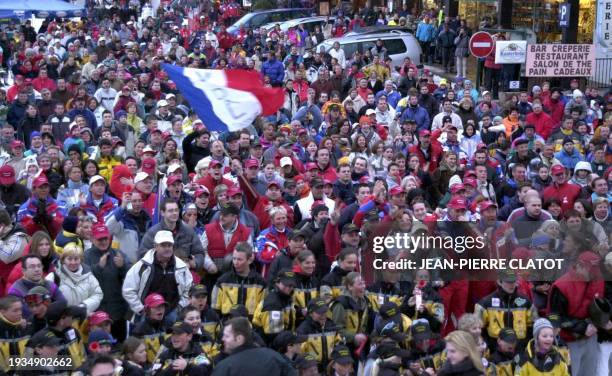 Des touristes et des habitants de la station de La Toussuire lèvent les bras le 23 février 2002 en regardant, sur un écran géant, la course du...