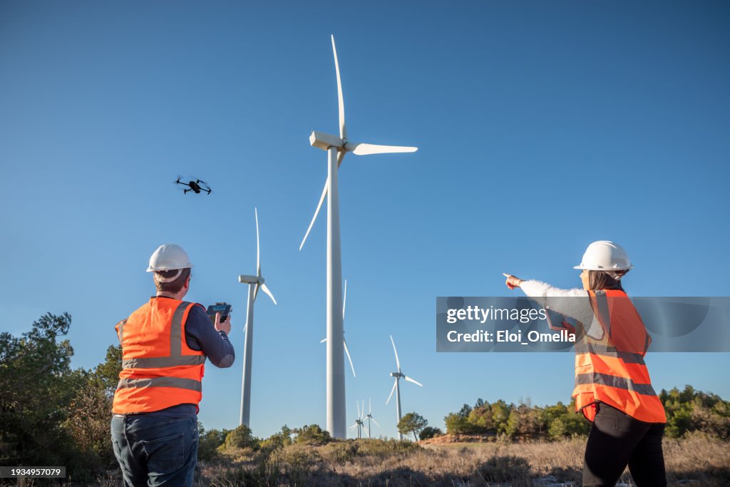 Engineer mechanic using drone for inspection in a windmill farm park