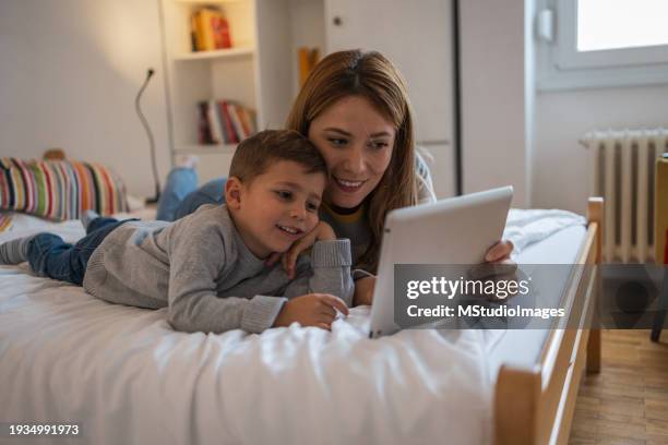 mother and son are lying on the bed and enjoying themselves - parental control stock pictures, royalty-free photos & images