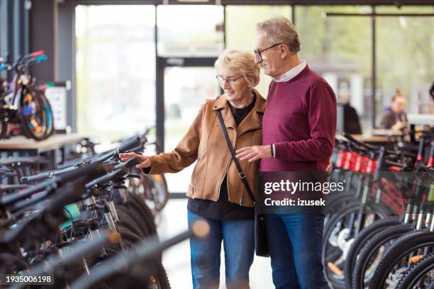 senior couple in bicycle shop - shopping with bike stock-fotos und bilder