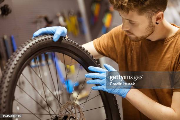 serviceman repairing a tire on a bicycle - repairing bike stock pictures, royalty-free photos & images