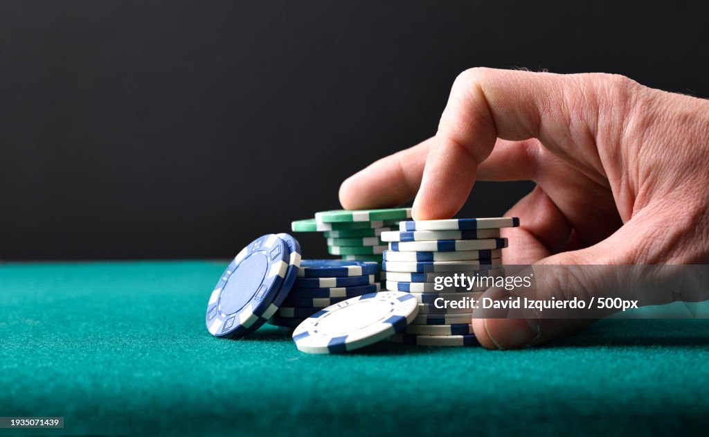 Cropped hand playing poker on table
