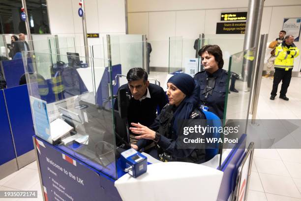 Prime Minister Rishi Sunak looks at the passport control unit next to Border Force officer Bazzar at Gatwick Airport, on January 18, 2024 in London,...