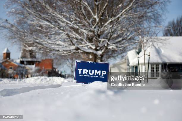 Campaign sign supporting Republican presidential candidate former President Donald Trump is stuck in the snow on January 15 in Pella, Iowa. Iowa...