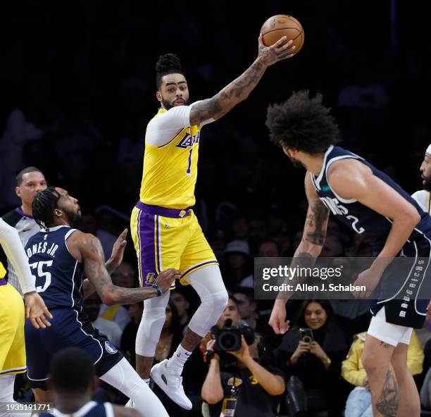 Los Angeles, CA Lakers point guard D'Angelo Russell, #1, center, grabs a rebound over Mavericks forward Derrick Jones Jr., #55, left, and Mavericks...