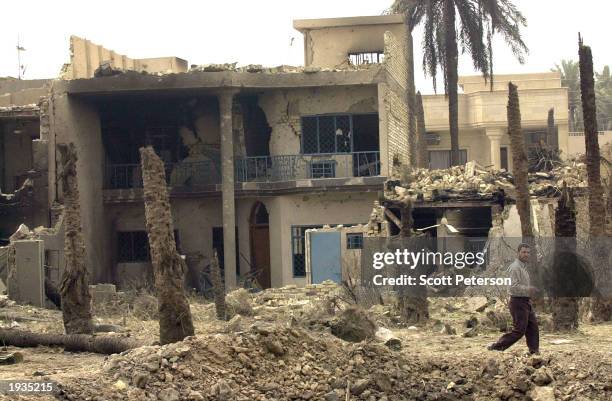 Baghdad resident walks past the remains of Abdulkarim al-Fardousi's house with a 10-foot-deep crater in the front April 15, 2003 in Baghdad, Iraq....