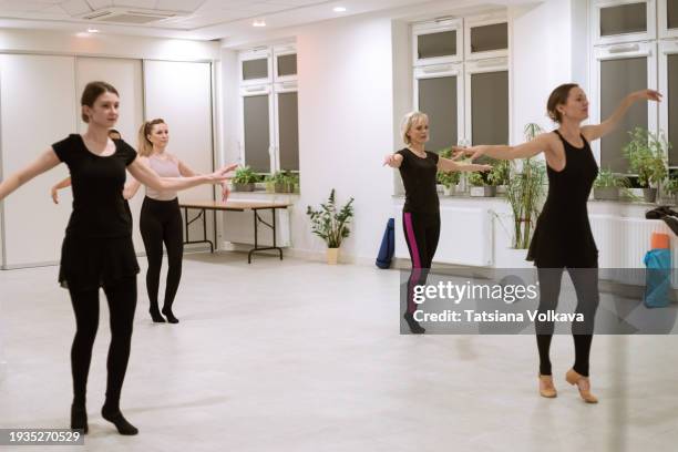 within serene ambiance of ballet studio, four adult ladies harmoniously learning ballet steps in front of mirror, raising arms and keeping hands wide open. - ambiance girly stock pictures, royalty-free photos & images