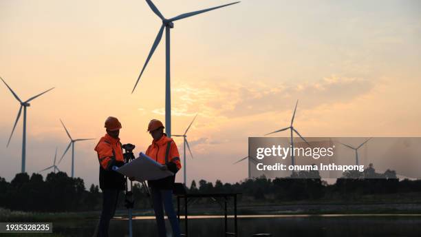 wind turbine engineers work with blueprint drawing and survey cameras at find turbine farm - camera operator stock pictures, royalty-free photos & images