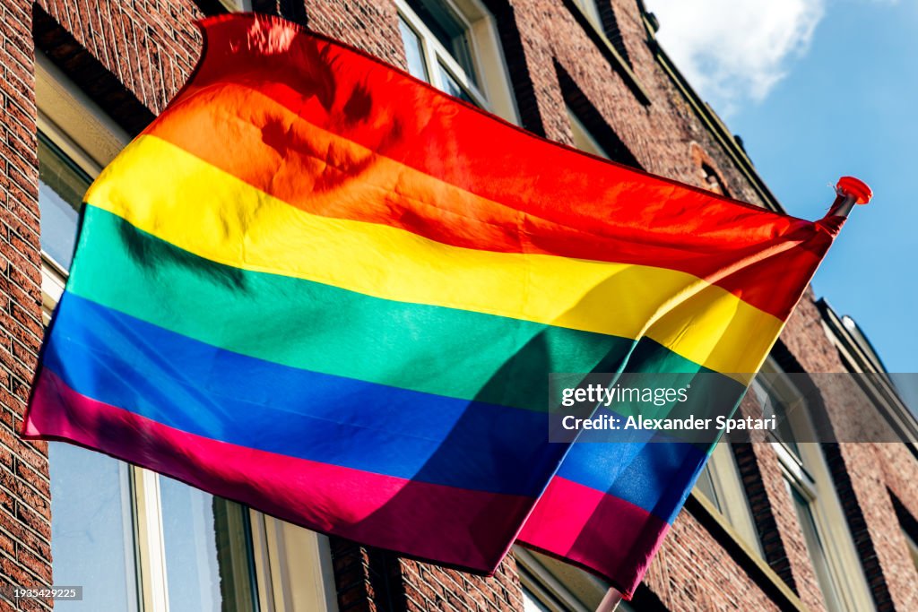 Rainbow LGBTQI+ pride flag on a building waving in the wind on a sunny day