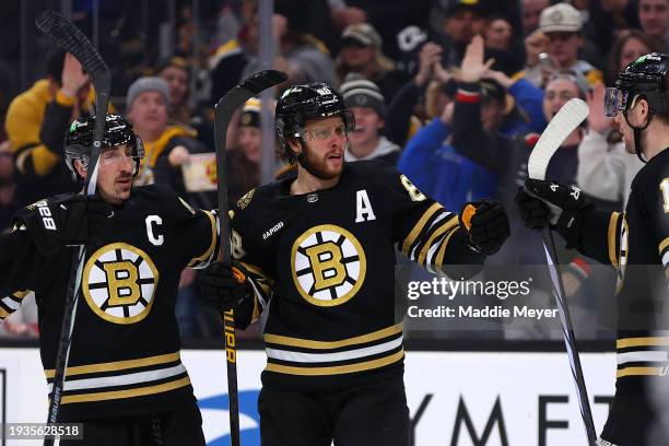 David Pastrnak of the Boston Bruins celebrates with Brad Marchand and Charlie Coyle after scoring a goal against the New Jersey Devils during the...