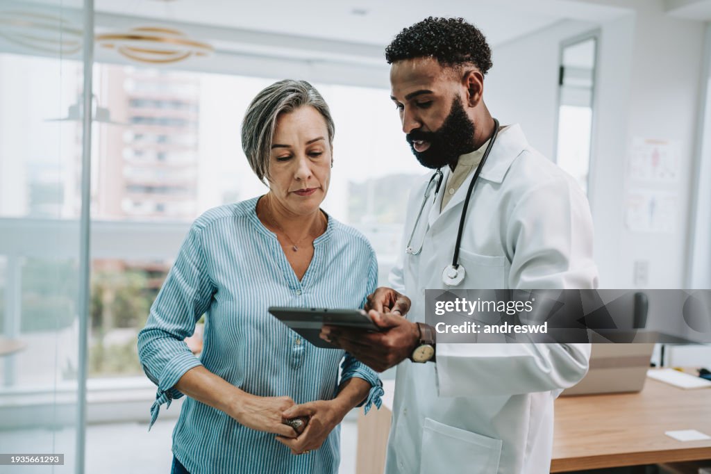 Doctor talking to patient holding digital tablet