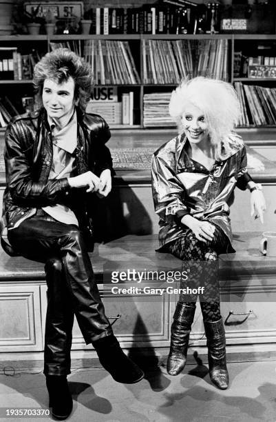 View of married American New Wave musicians Terry Bozzio and Dale Bozzio, both of the group Missing Persons, as they sit on a low stage during an...