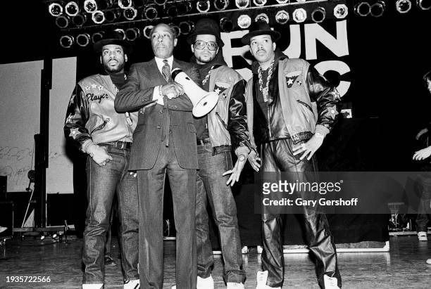 View of American educator and Eastside High School principal Joe Louis Clark with the members of American Hip Hop group Run-DMC on a stage at the...